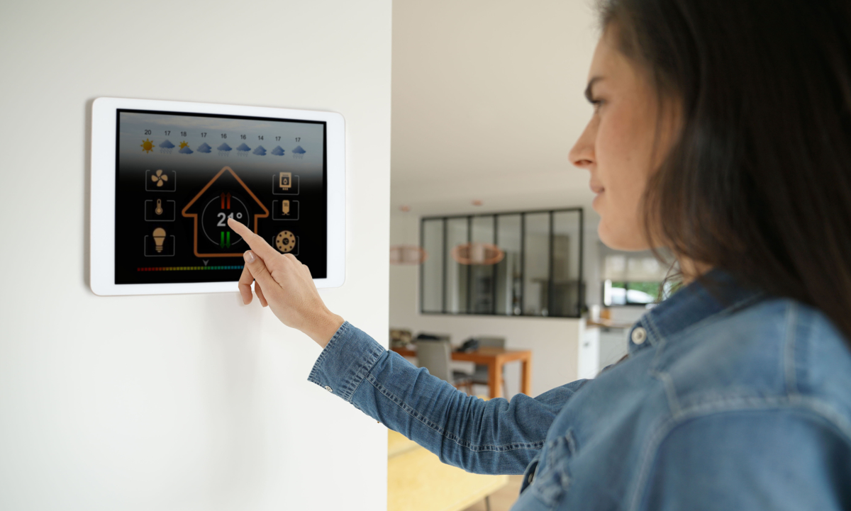 Chauffage appartement neuf — Une femme qui ajuste la température de son intérieur grâce à une interface connectée