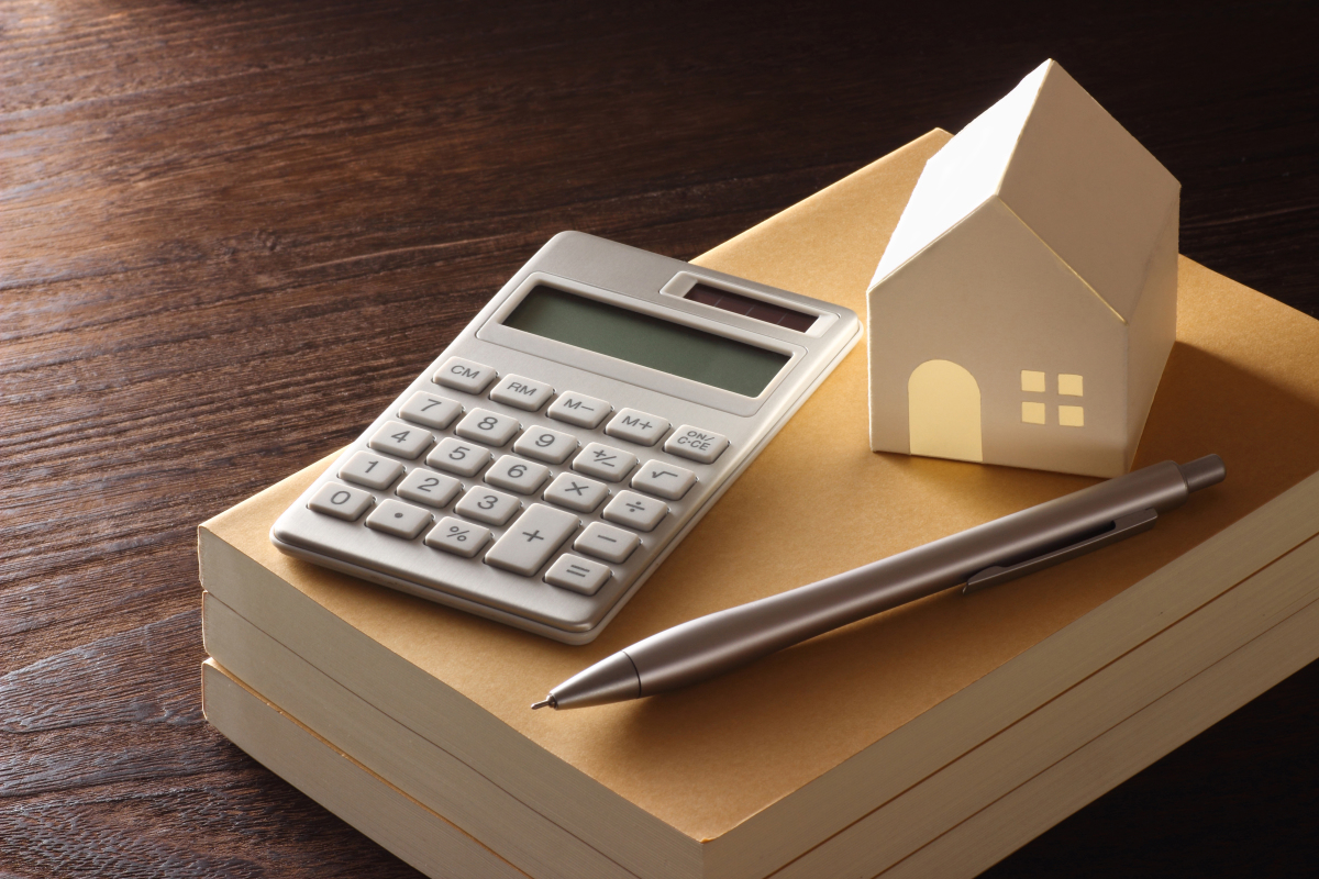 Premier investissement locatif – Une calculatrice et une petite maison sur un dossier