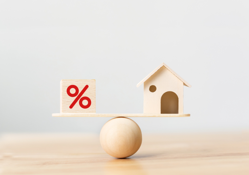 Qui peut investir en Pinel plus – Une maison en bois et un cube représentant un pourcentage en équilibre sur une boule en bois