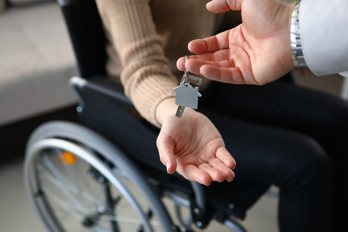 Pourquoi acheter dans le neuf – Un agent immobilier remet les clés à une personne en fauteuil roulant