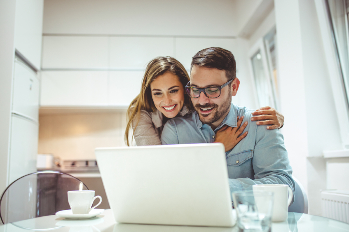 les taux de prêt immobilier 2022 - couple heureux devant un ordinateur portable pour simuler leur projet immobilier 