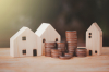 investisseur immobilier – Des maisons miniatures en bois avec des piles de pièces montrant la croissance d’un investissement immobilier