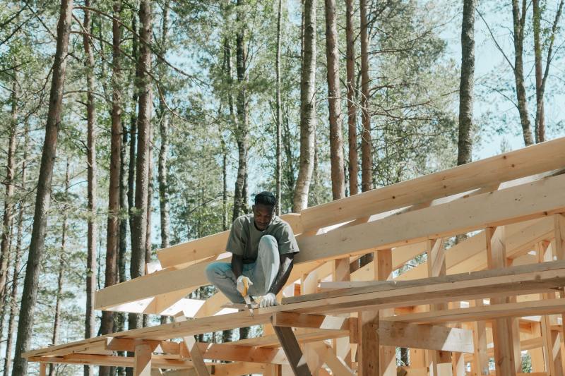 Label EcoQuartier – Un ouvrier construit une maison en bois, un matériau biosourcé