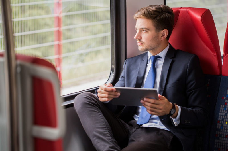 un proprietaire tient une tablette sur ses genoux dans un train
