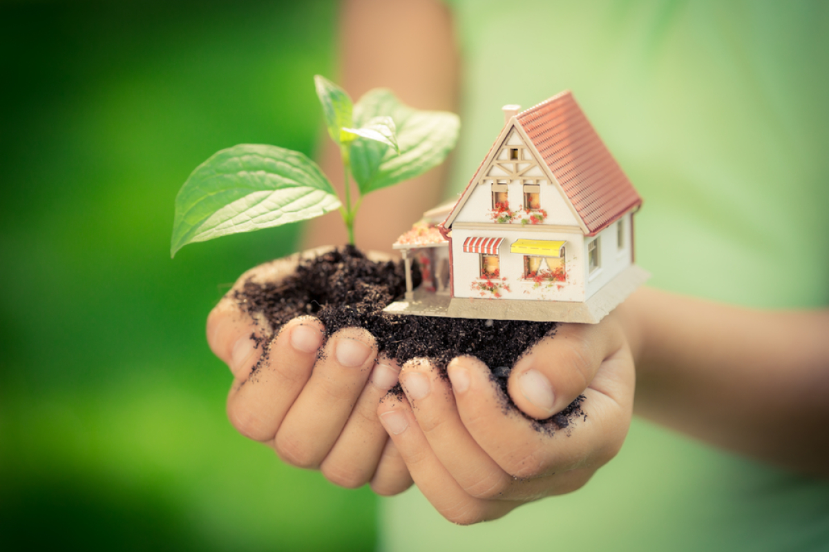 Qu'est-ce que le taux d’effort – Des mains tenant de la terre sur laquelle se trouve une pousse de plante et une maison miniature