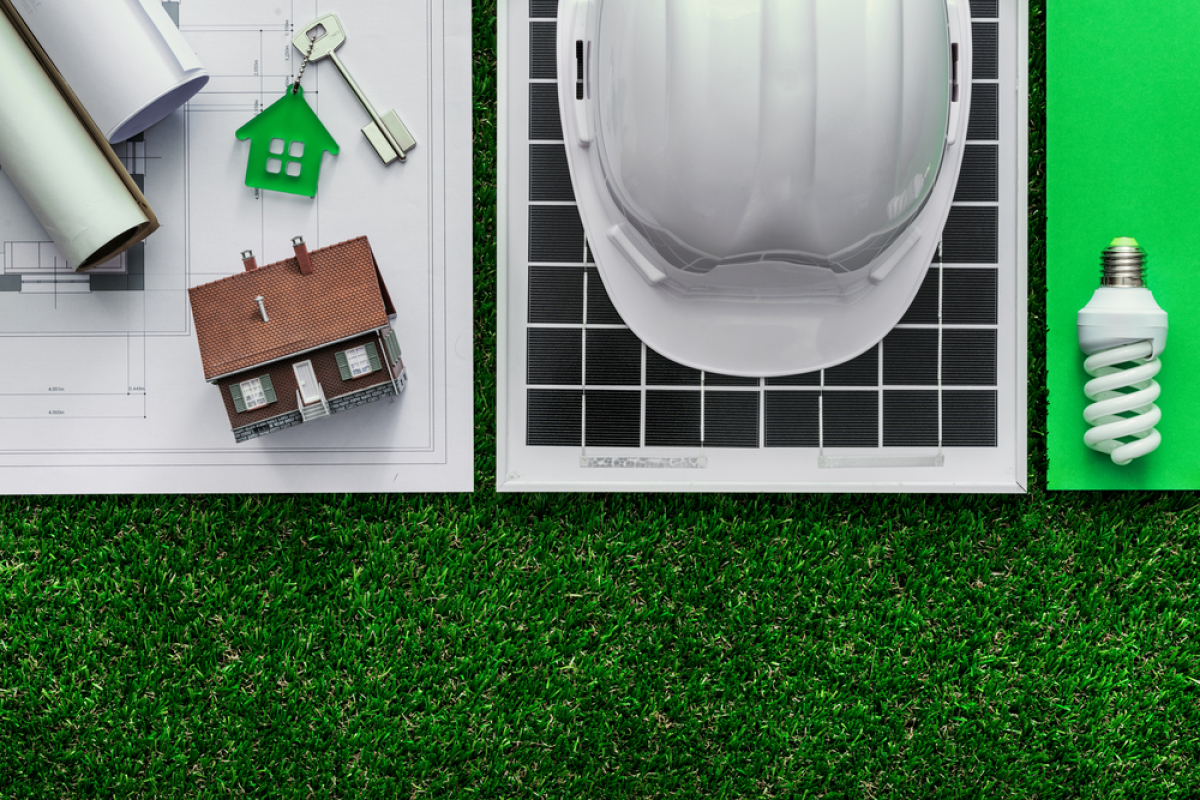 immobilier éco responsable – casque de chantier, ampoule LED, panneau solaire, plans et clés de maison verte