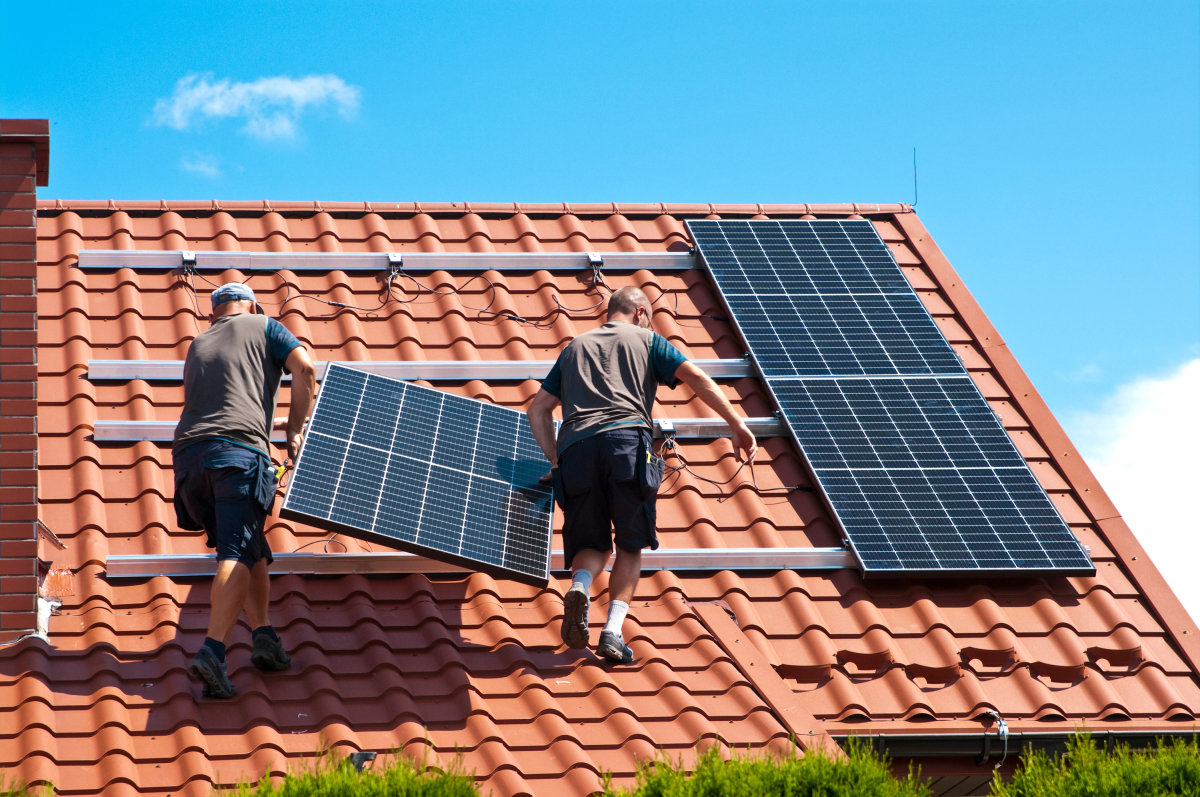 carnet d'information du logement  — deux hommes installent des panneaux solaires sur le toit d’un logement